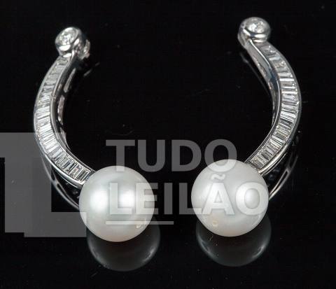 Par de brincos em ouro branco 18k, com 2 diamantes redondos ao topo de aproximadamente 0,06 ct cada, e corpo curvo cravejado com 42 diamante...