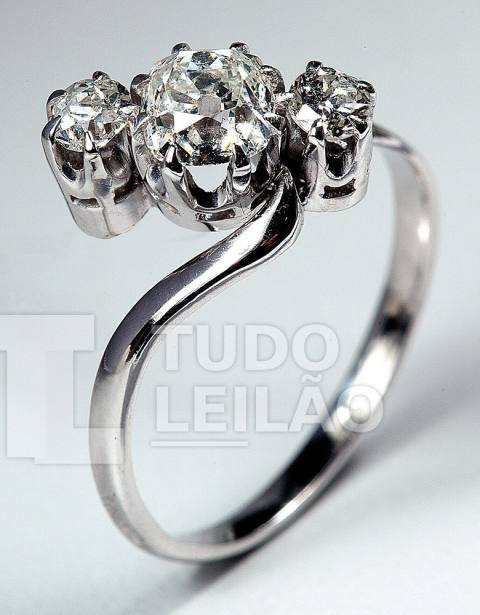 Anel de platina com design torcido, com 3 diamantes, sendo o central de lapidação antiga com aproximadamente 0,55 ct e 2 diamantes redondos ...