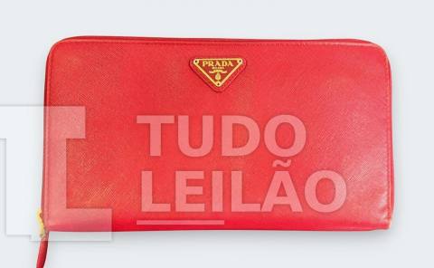 PRADA. Carteira em couro na cor vermelha, apresenta placa dourada com o logo, fechamento por zíper. Parte interna com card slots, bolsos par...